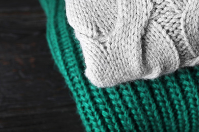 Image of Folded warm sweaters on black wooden table, closeup