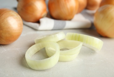 Photo of Rings of fresh onion and bulbs on grey table