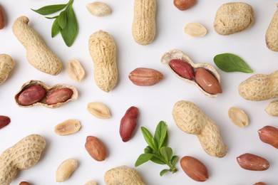 Photo of Fresh peanuts and leaves on white table, flat lay