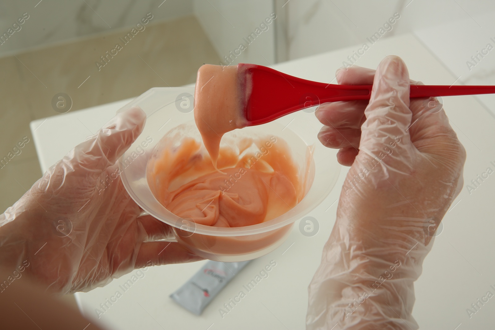 Photo of Woman preparing hair dye in bowl at home, closeup