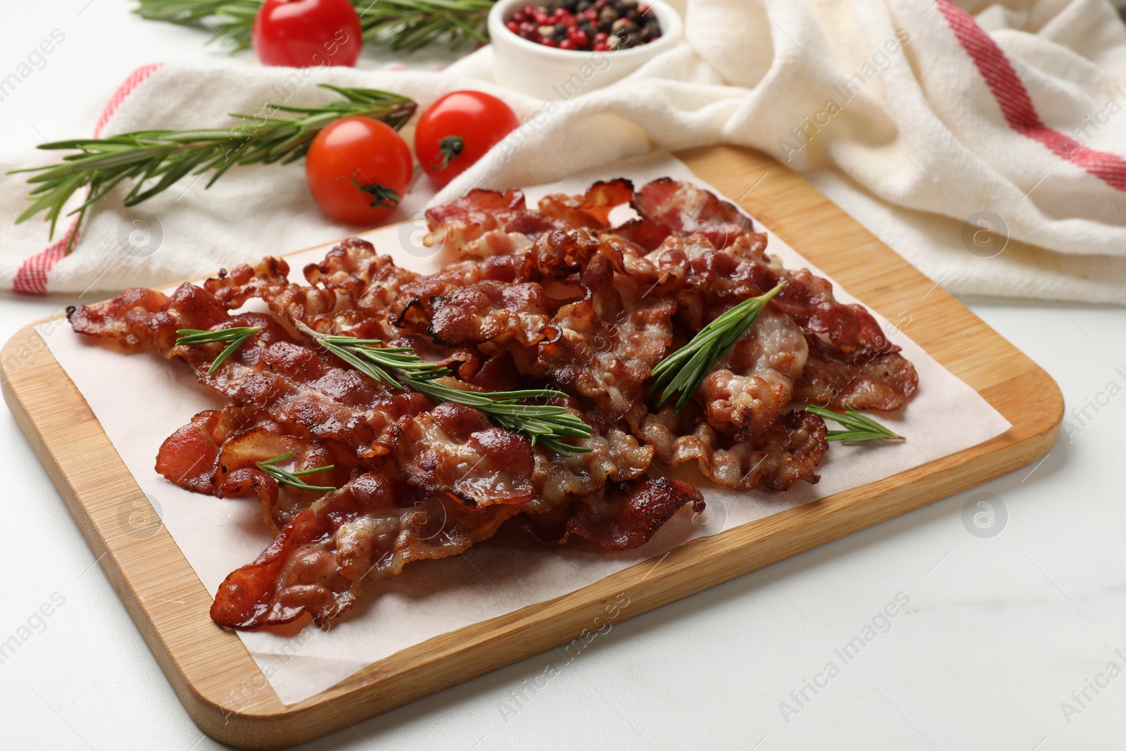 Photo of Slices of tasty fried bacon with rosemary on white table