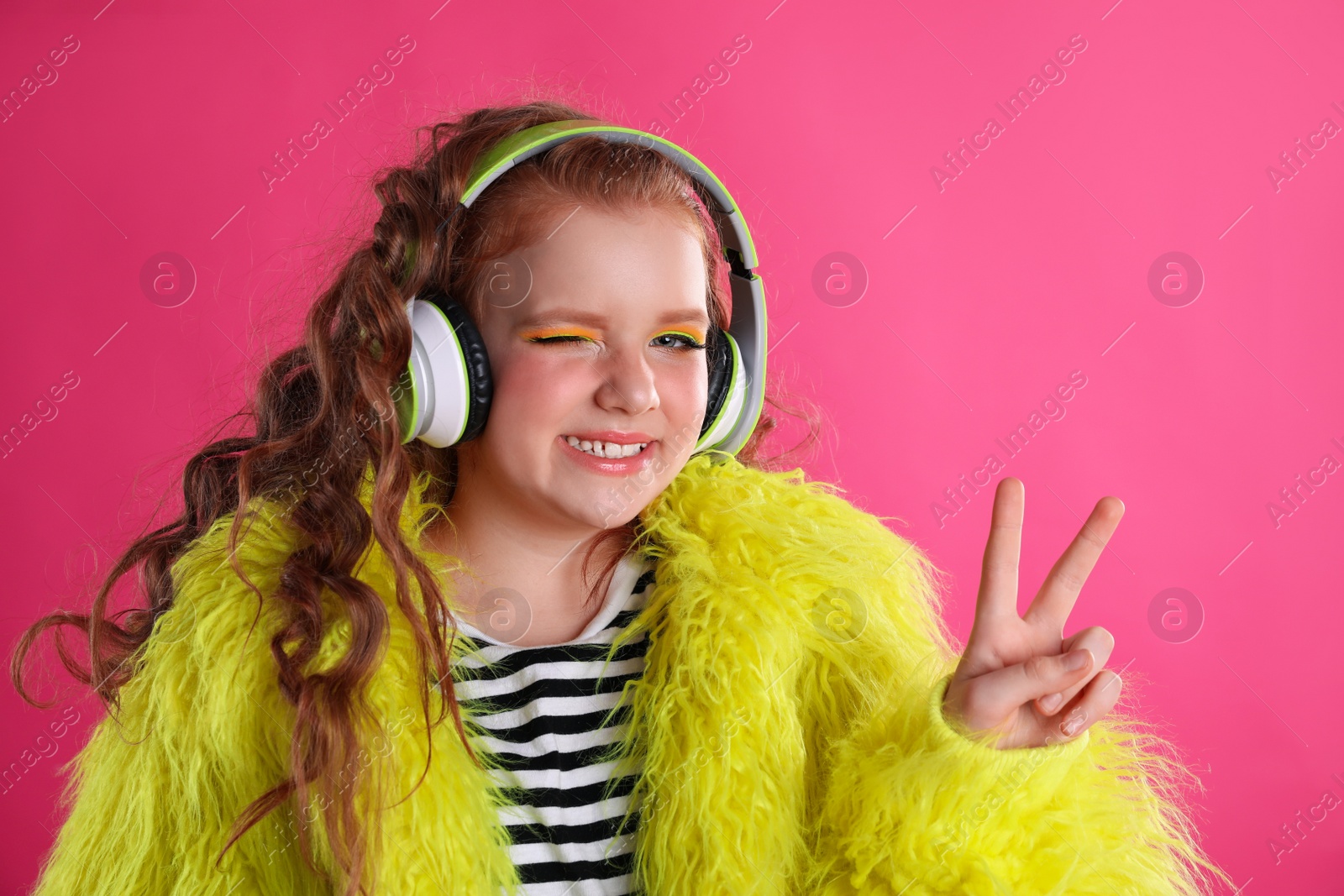 Photo of Cute indie girl with headphones on pink background