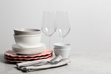 Photo of Beautiful ceramic dishware, glasses and cutlery on light grey table, space for text