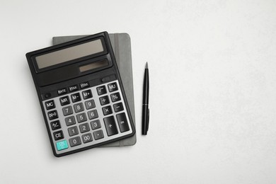 Calculator and office stationery on white table, top view. Space for text