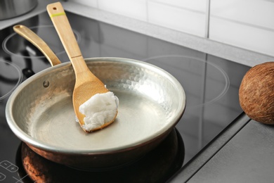 Wooden spatula with coconut oil in frying pan. Healthy cooking