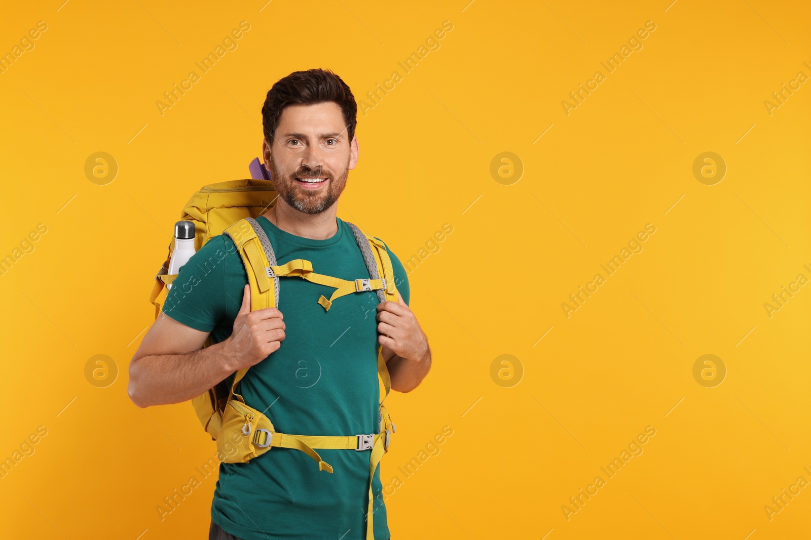 Photo of Happy man with backpack on orange background, space for text. Active tourism