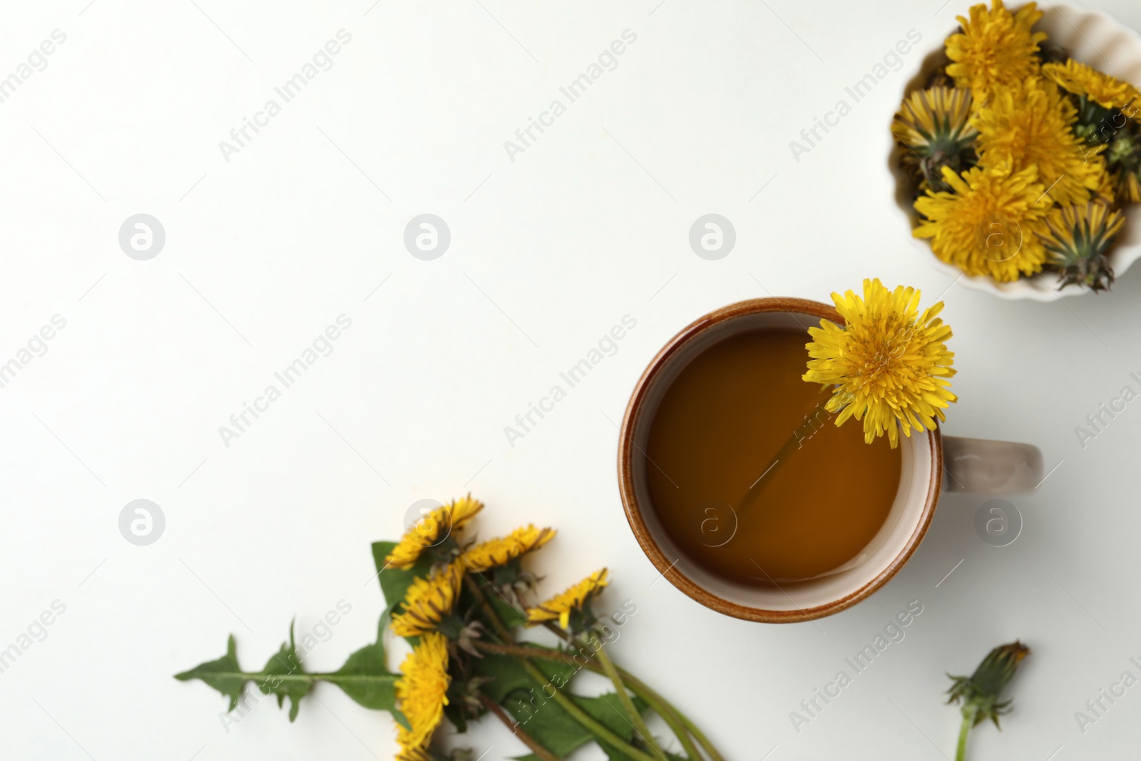 Photo of Delicious fresh tea and beautiful dandelion flowers on white background, top view. Space for text