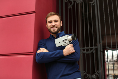 Young man with vintage video camera outdoors