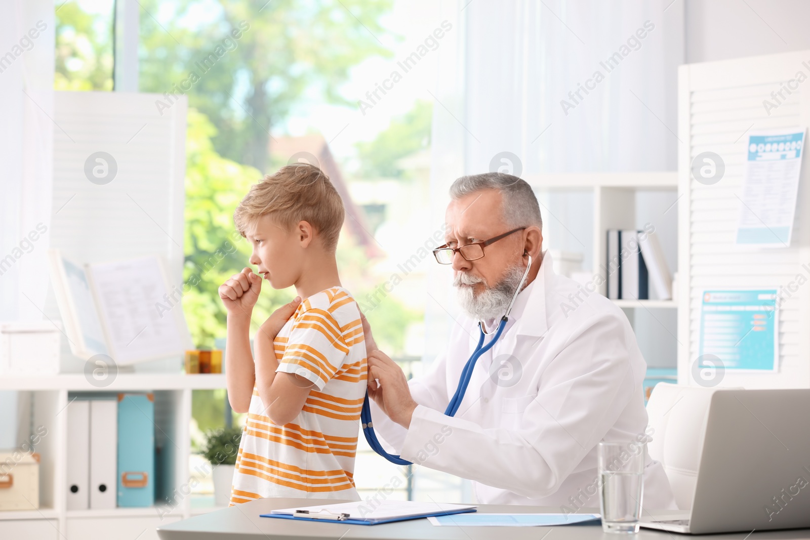 Photo of Doctor examining coughing little boy at clinic