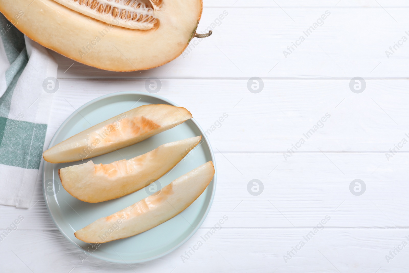 Photo of Sliced delicious ripe melon on white wooden table, flat lay. Space for text