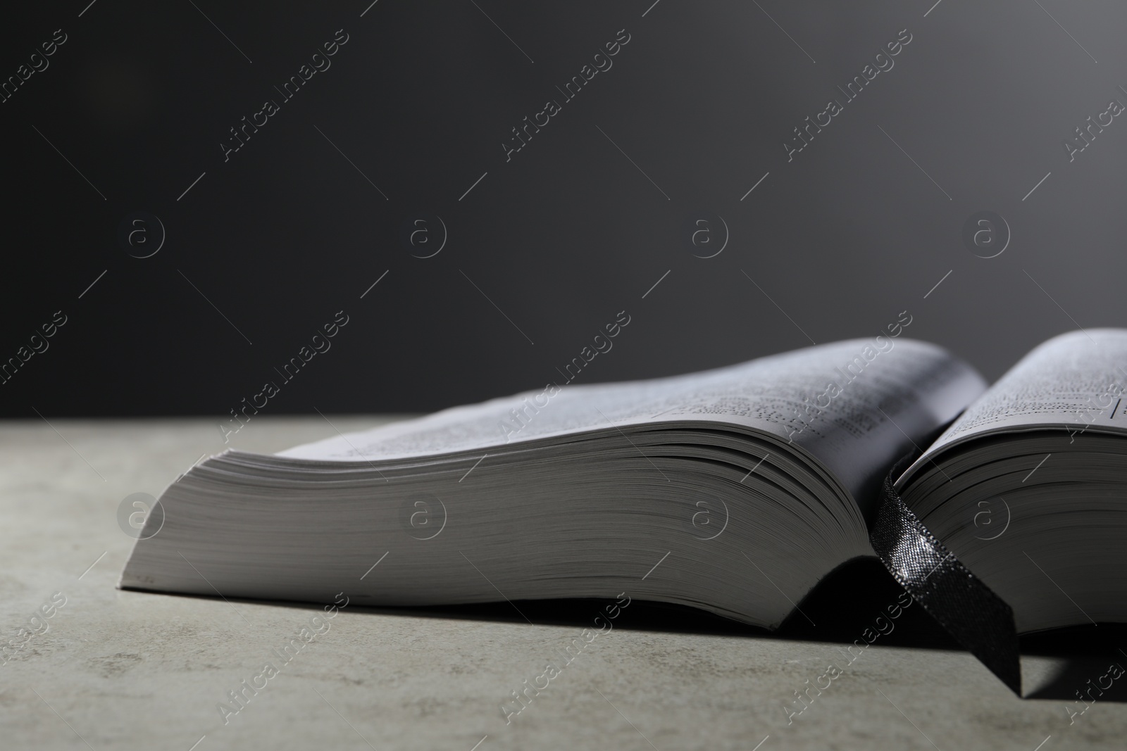 Photo of Open Bible on light gray table, space for text. Christian religious book