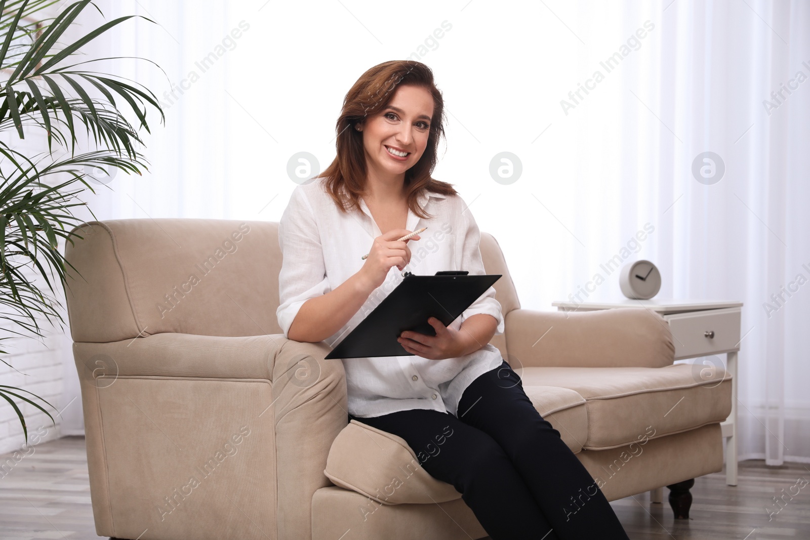 Photo of Portrait of psychotherapist with clipboard on sofa in office