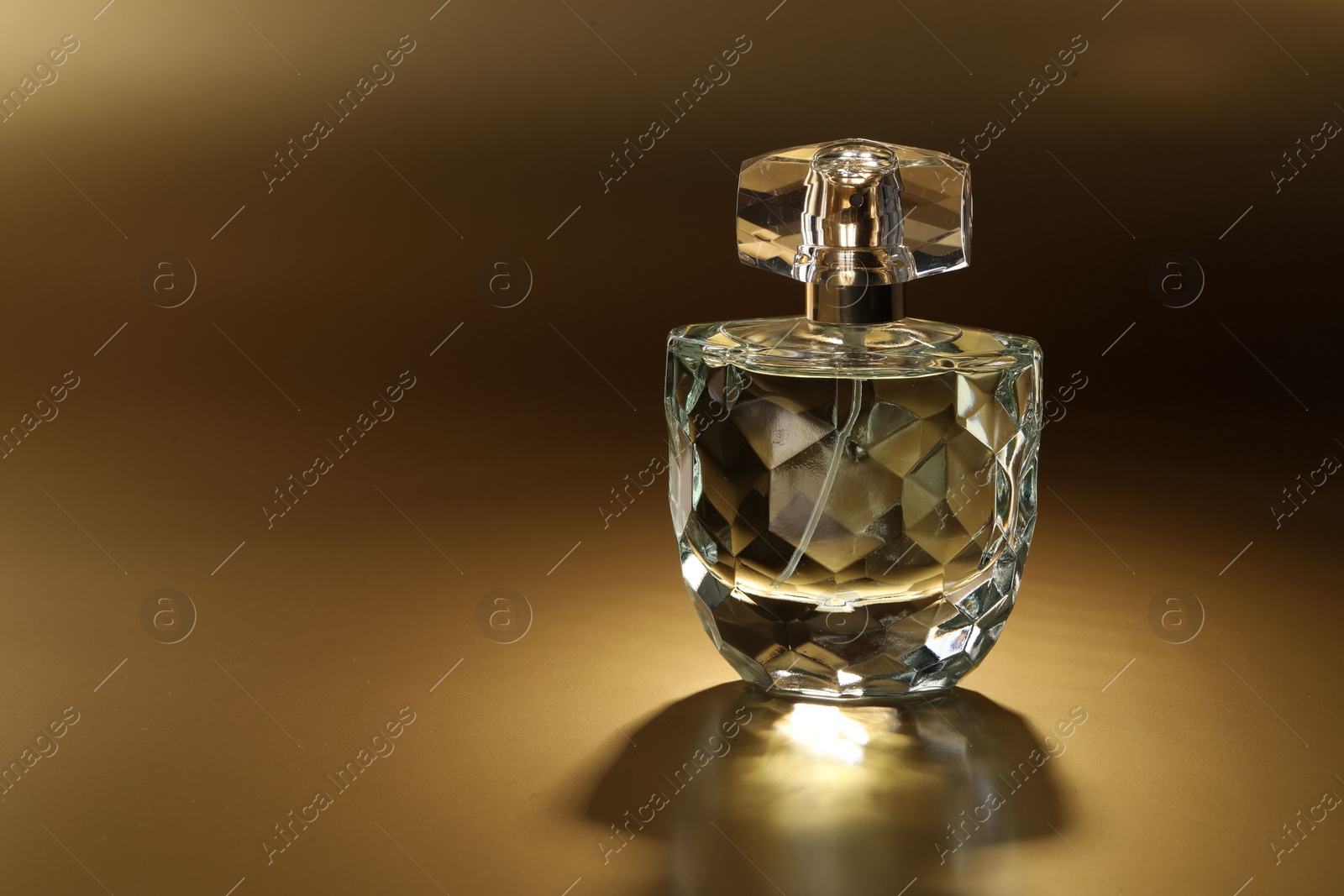 Photo of Luxury women's perfume. Sunlit glass bottle on golden background, space for text