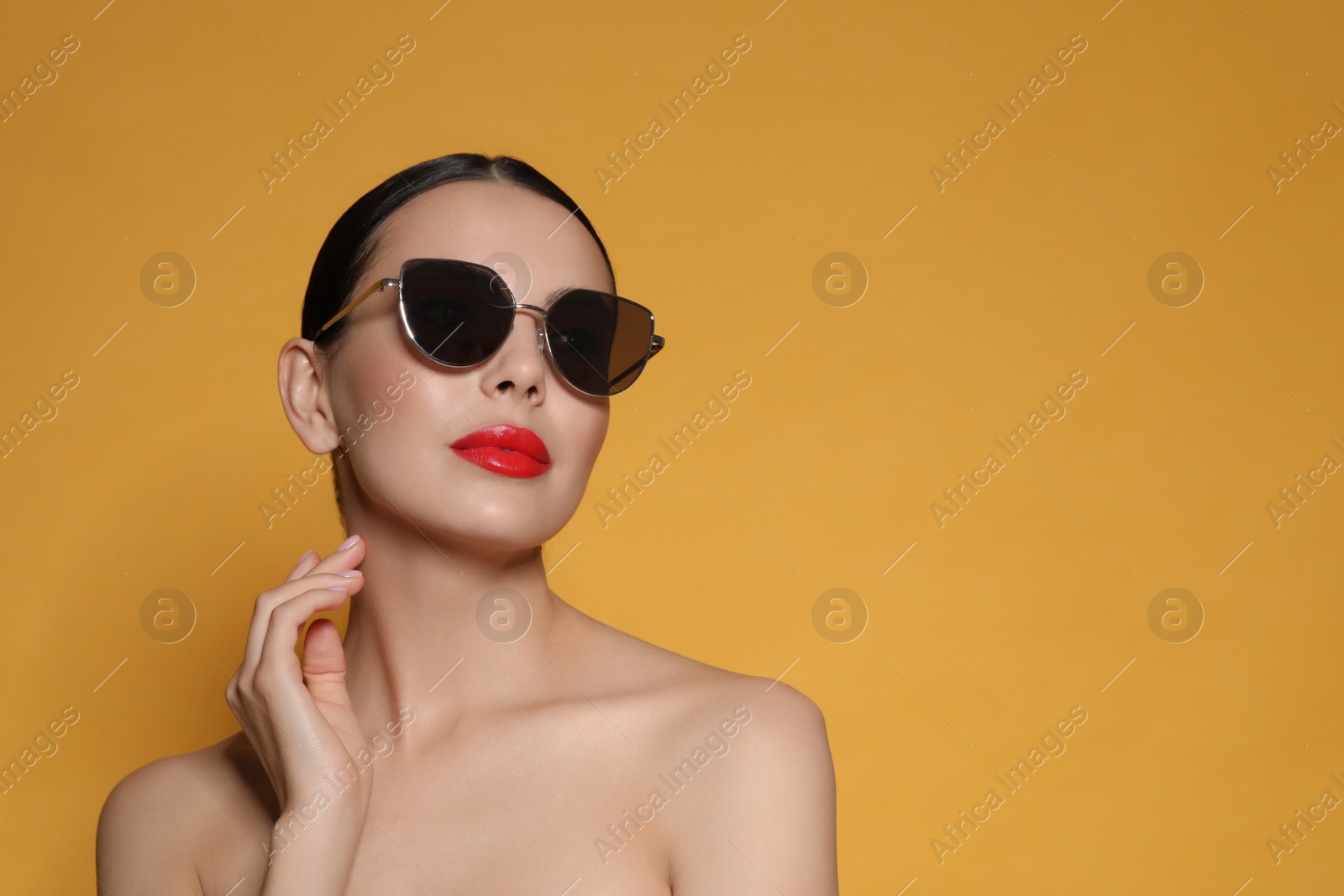 Photo of Attractive woman in fashionable sunglasses against orange background. Space for text