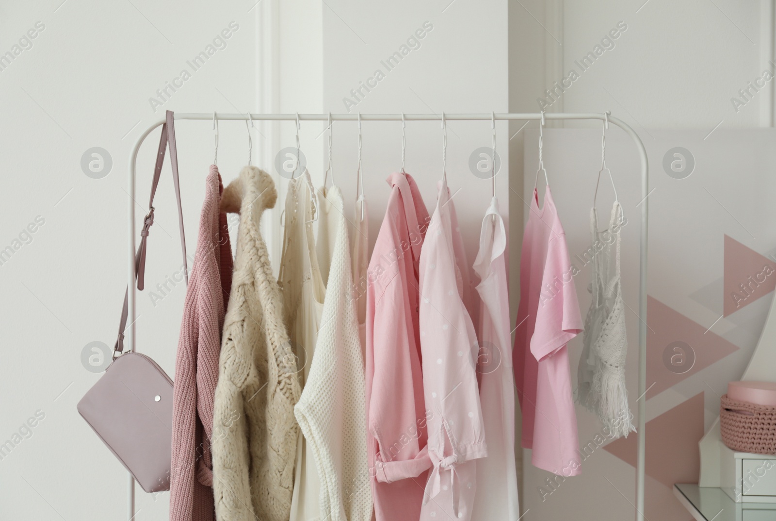 Photo of Rack with stylish clothes near white wall in dressing room