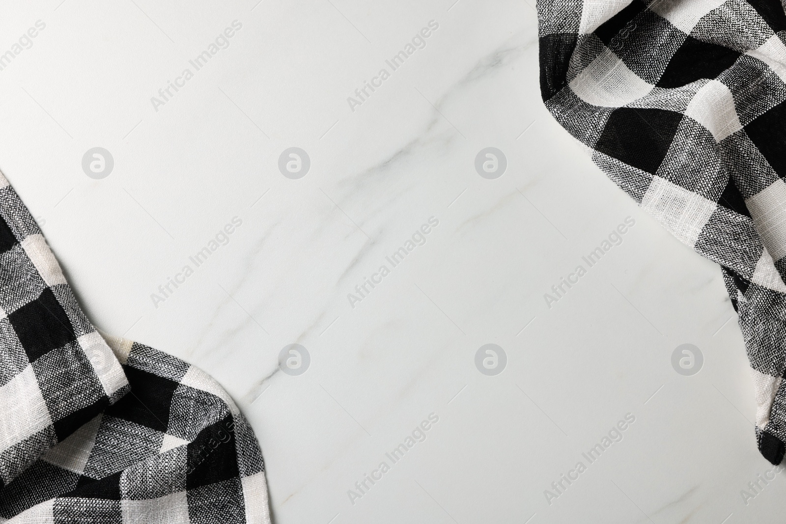 Photo of Black checkered tablecloths on white marble table, flat lay. Space for text