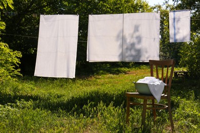 Photo of Washing line with clean laundry and clothespins outdoors