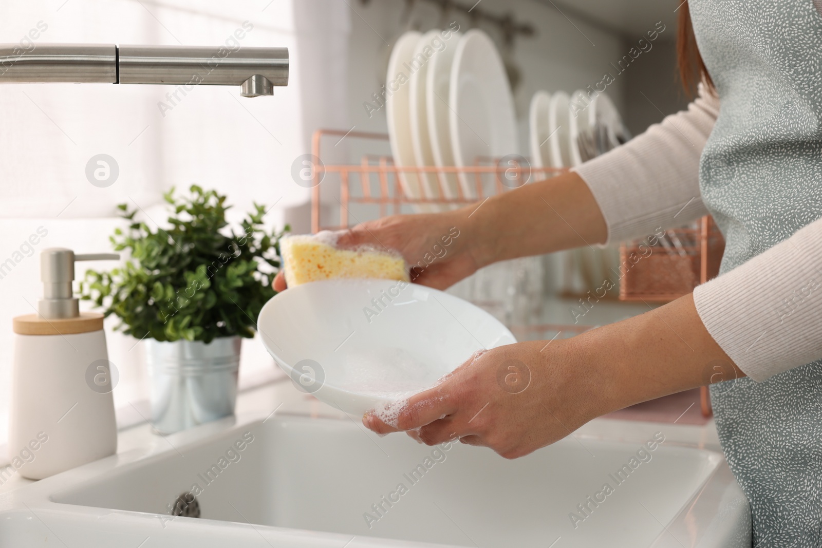 Photo of Woman washing bowl at sink in kitchen, closeup