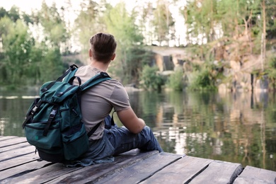 Young man on wooden pier near lake. Camping season