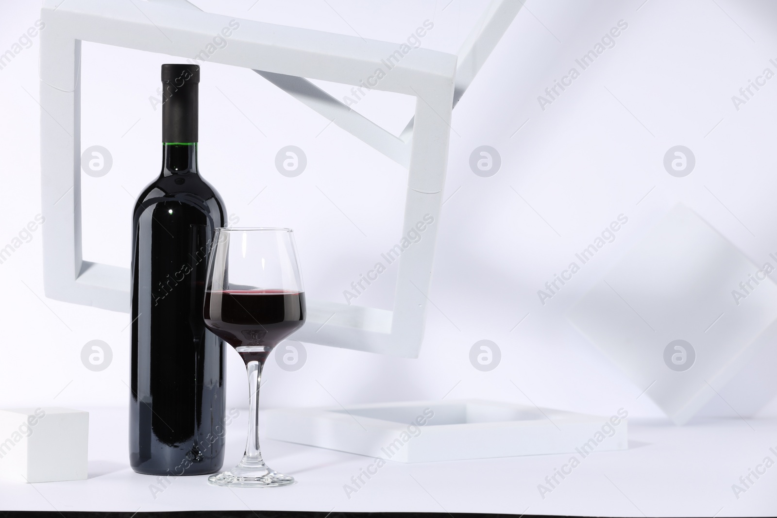 Photo of Stylish presentation of delicious red wine in bottle and glass on white background. Space for text