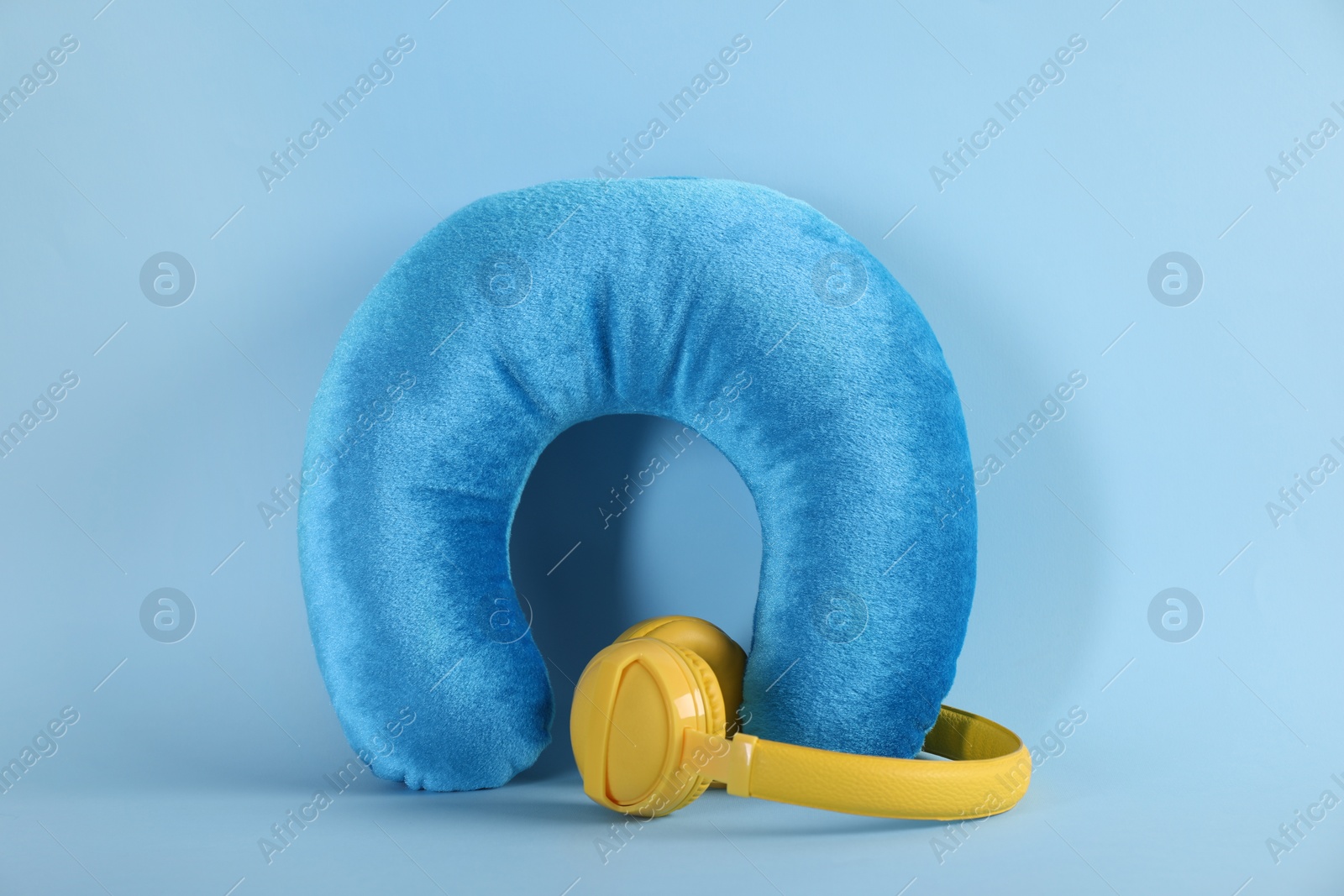 Photo of Travel pillow and headphones on light blue background