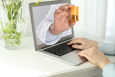 Image of Ordering medications online. Pharmacist giving pills from laptop screen