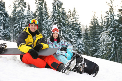 Happy couple with snowboards on hill. Winter vacation