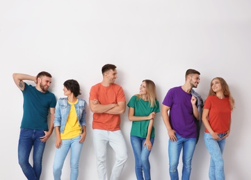 Photo of Group of young people in jeans and colorful t-shirts on light background