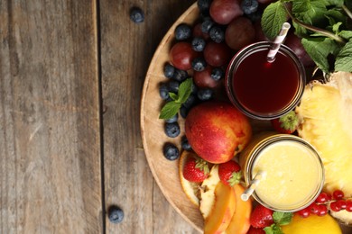 Photo of Delicious colorful juices in glasses and fresh ingredients on wooden table, top view. Space for text