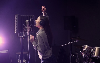 Photo of Young singer with microphone recording song in studio. Space for text