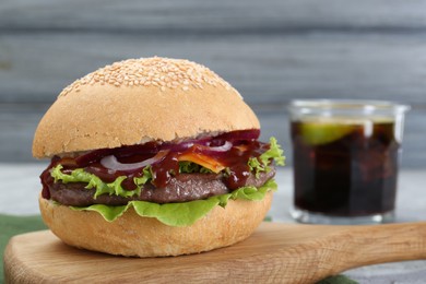 Photo of Board with delicious cheeseburger on table, closeup