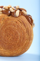 One supreme croissant with chocolate paste and nuts on light blue background, closeup. Tasty puff pastry