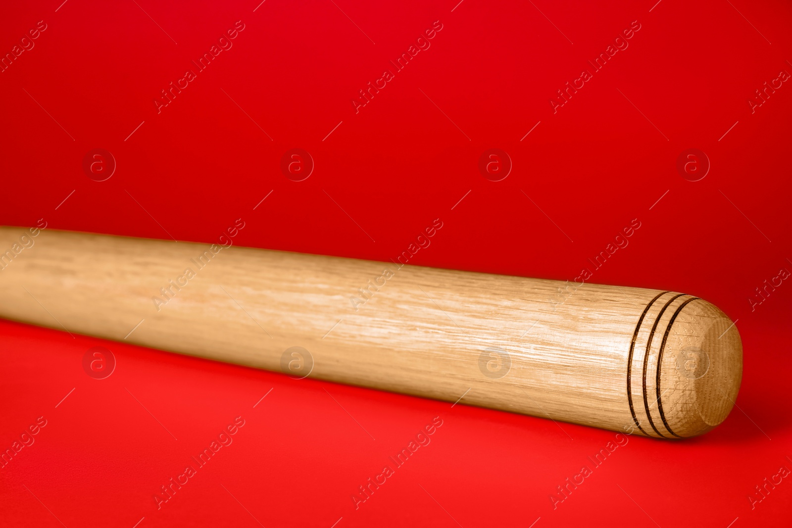 Photo of Wooden baseball bat on red background, closeup. Sports equipment