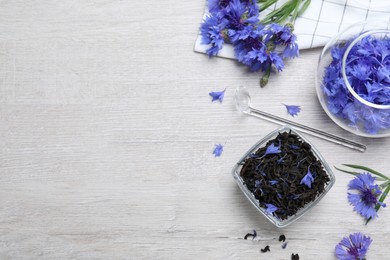 Photo of Composition with dry tea leaves and cornflowers on white wooden table, flat lay. Space for text