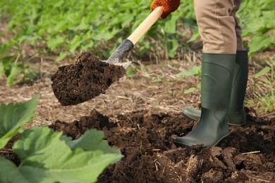 Photo of Worker digging soil with shovel outdoors, closeup