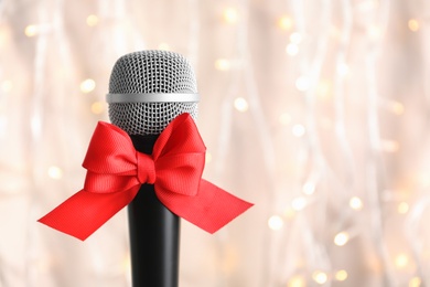 Photo of Microphone with bow on blurred background. Christmas music concept