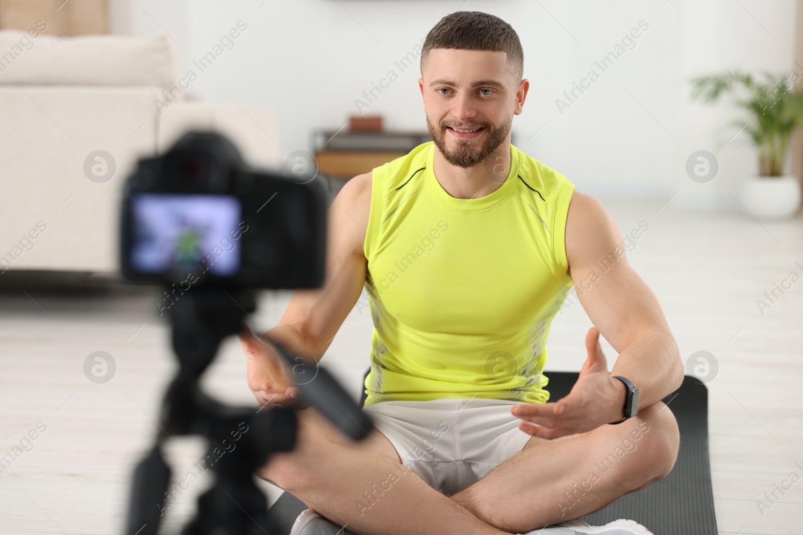 Photo of Trainer recording fitness lesson on camera at home