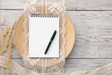 Guest list. Notebook, pen, spikelets and lace ribbons on wooden background, flat lay. Space for text