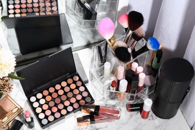 Photo of Bright lip glosses among different cosmetic products on white dressing table