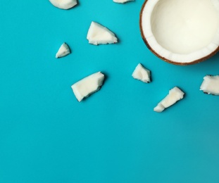 Photo of Fresh coconut pieces on blue background, flat lay. Space for text