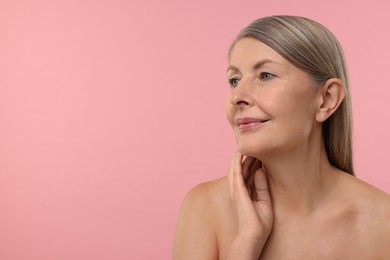 Beautiful woman touching her neck on pink background, space for text