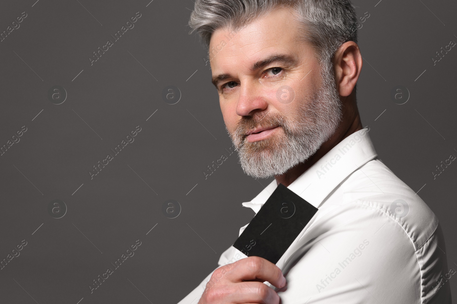 Photo of Handsome man holding blank business card on grey background. Space for text