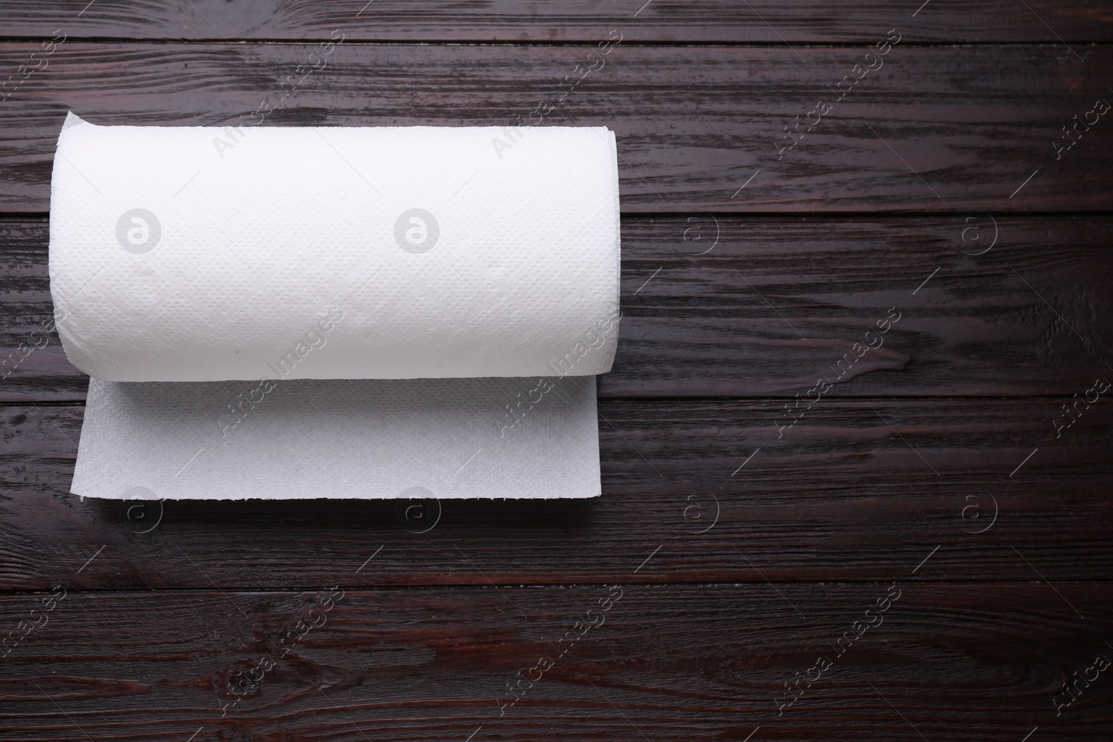 Photo of Roll of tissue towels on wooden table, top view. Space for text