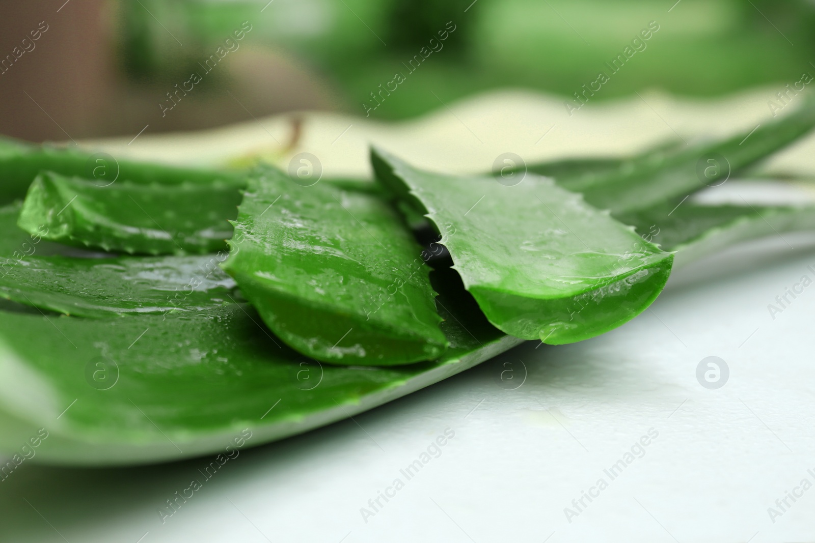 Photo of Fresh cut juicy aloe vera leaves on white table, closeup