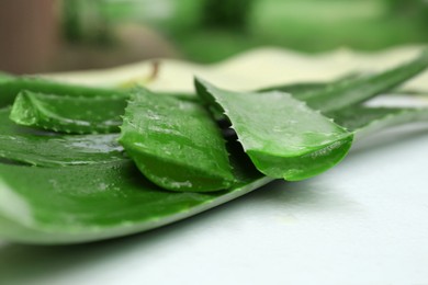 Photo of Fresh cut juicy aloe vera leaves on white table, closeup