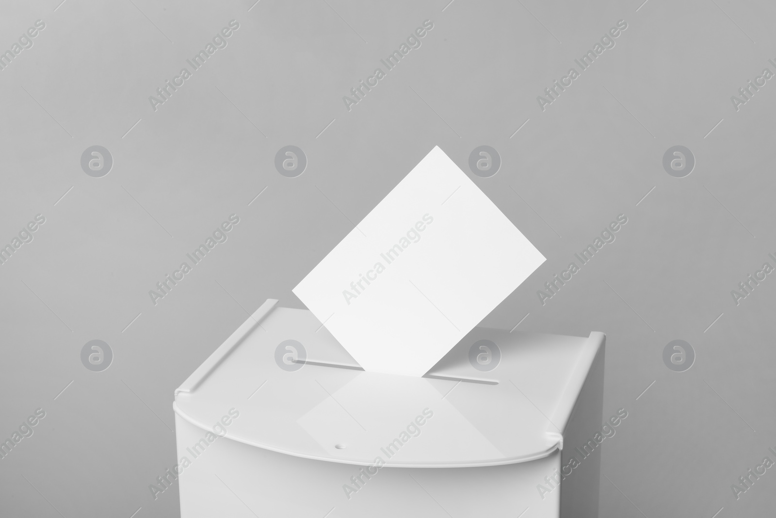 Photo of Ballot box with vote on light grey background, closeup. Election time