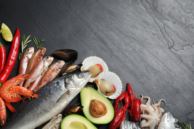 Fresh fish and different seafood on black table, flat lay. Space for text