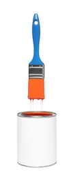 Photo of Brush with orange paint over can on white background