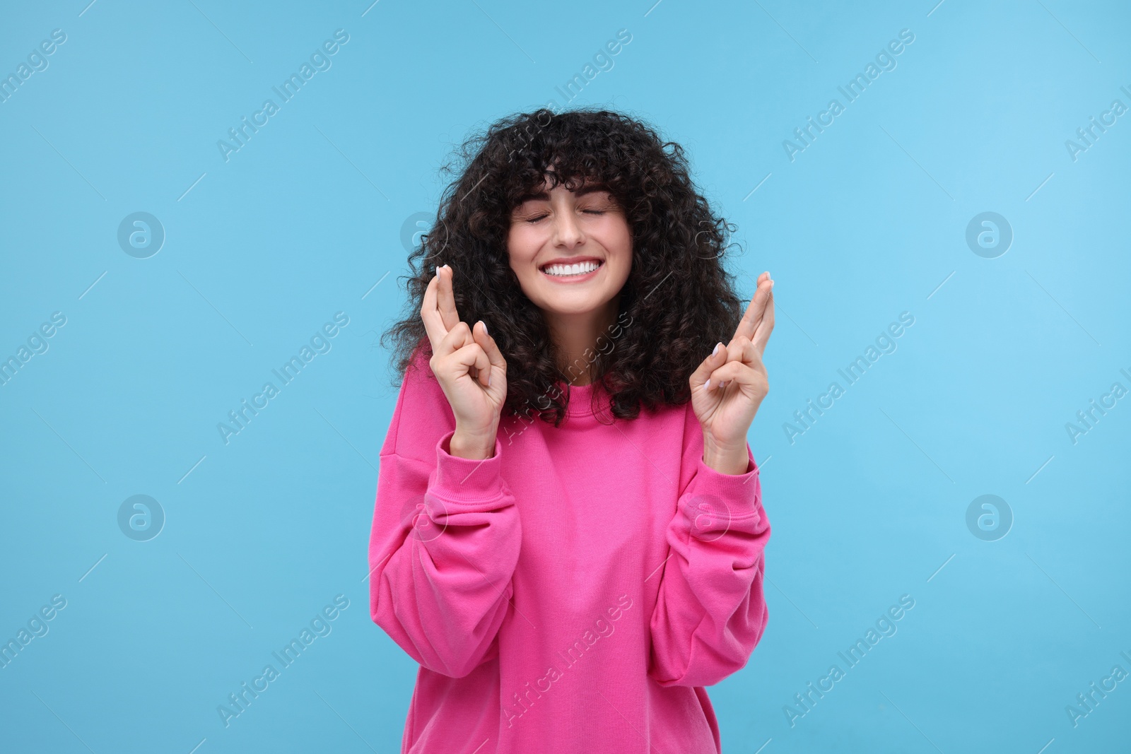 Photo of Woman crossing her fingers on light blue background