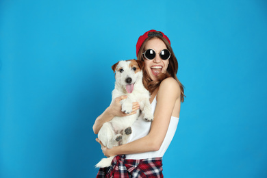 Young woman with her cute Jack Russell Terrier on light blue background. Lovely pet